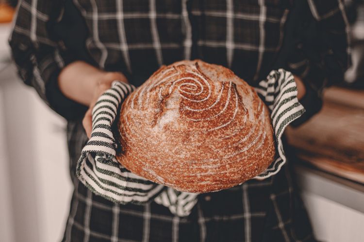 woman holding a fresh loaf of sourdough
