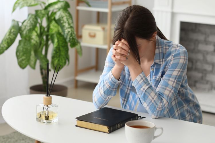 woman praying at desk in office